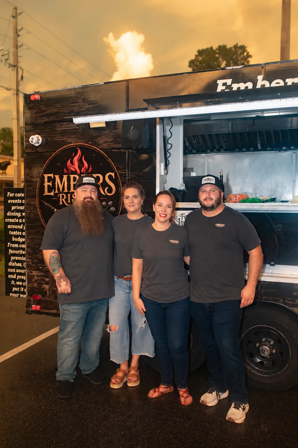 The Embers Rising team standing together in front of their food trailer